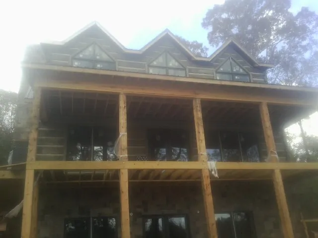 Dormers and porch framing on a large log home under construction — Roof Coating work by our crew in Brookfield