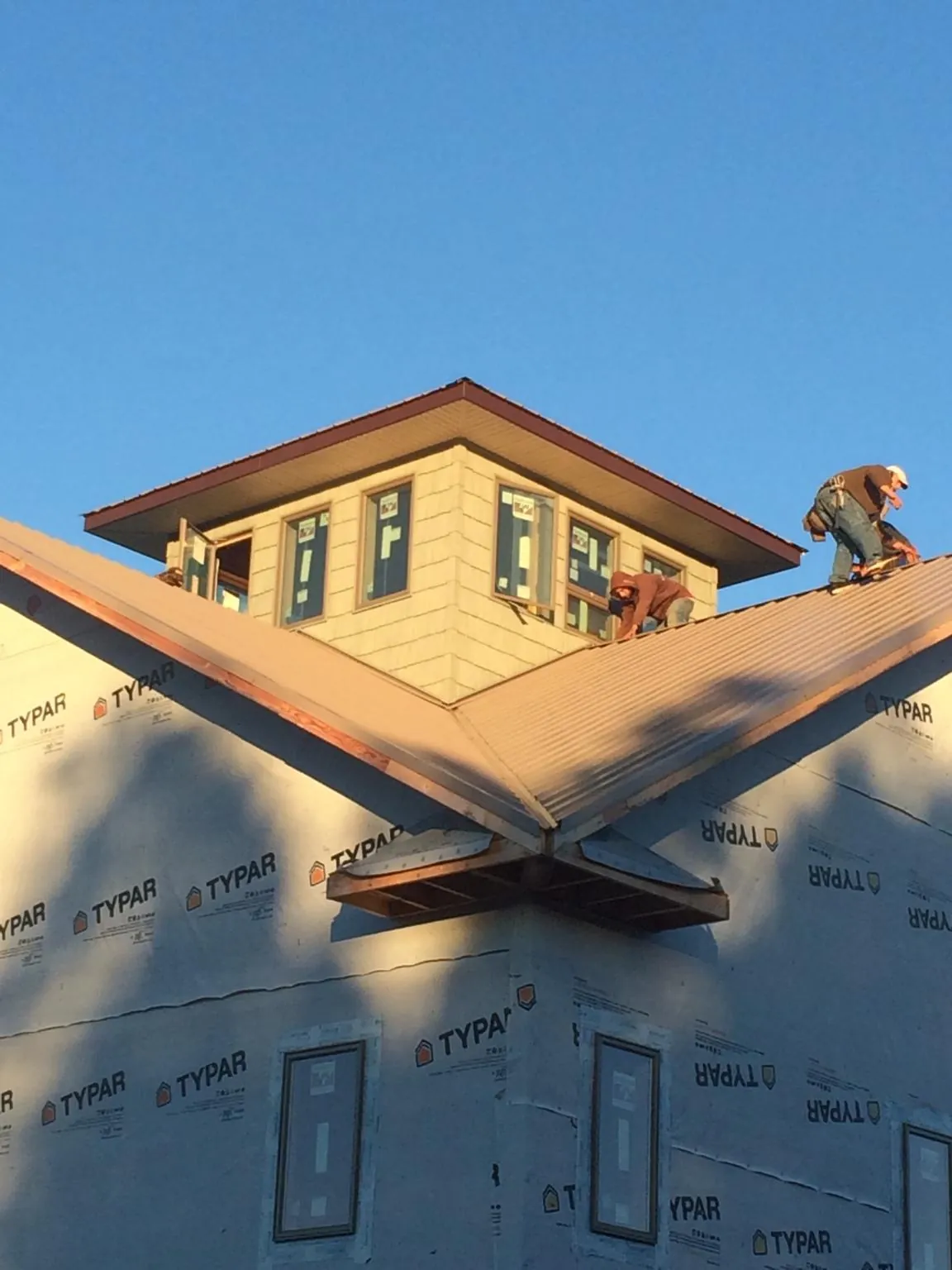 Roofers working around a rooftop cupola on a new metal roof at sunset — Roof Waterproofing in Brookfield by Roofing Brothers
